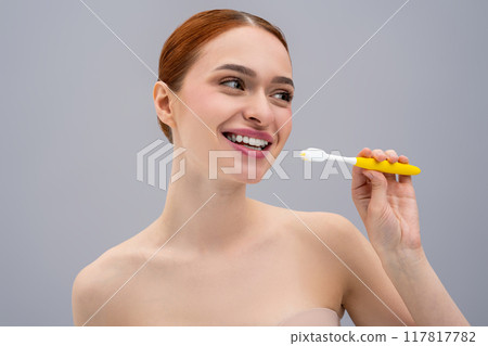 Happy young woman brushing teeth and looking enjoyed Happy young woman brushing teeth and looking enjoyed 117817782
