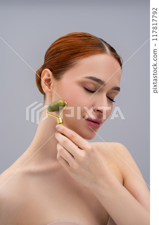 Cute ginger woman with a face roller in hands 117817792
