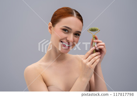 Cute ginger woman with a face roller in hands Cute ginger woman with a face roller in hands 117817798