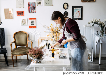 Creating unique epoxy resin art in a cozy studio decorated with floral arrangements during a DIY session Creating unique epoxy resin art in a cozy studio decorated with floral arrangements during a DIY session 117818095