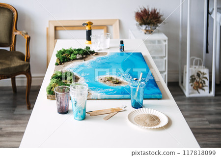 Resin art project depicting a coastal landscape, creative DIY craft, handmade ocean scene, artistic home decor, nature-inspired design, hobbyist workspace, epoxy resin artwork 117818099