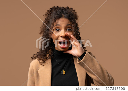 Attention, portrait of african young woman shouting,holding hand near open mouth Attention, portrait of african young woman shouting,holding hand near open mouth 117818300
