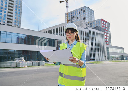 Industrial worker female builder with working documents, outdoor construction 117818340