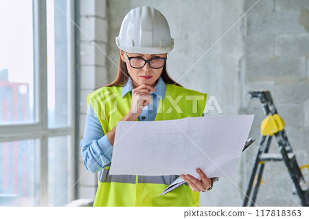 Technical profession woman in protective vest helmet working on construction 117818363