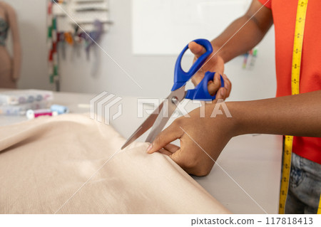 Unrecognizable fashion designer tailor or sewer in workshop cutting textile with scissors Unrecognizable fashion designer tailor or sewer in workshop cutting textile with scissors 117818413