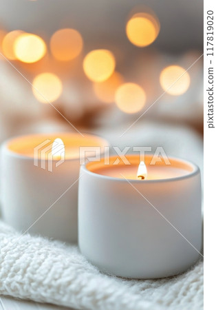 Candles glowing warmly on a cozy blanket with blurred bokeh lights in the background 117819020