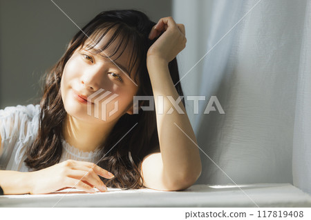 Woman by the window in the setting sun Woman by the window in the setting sun 117819408