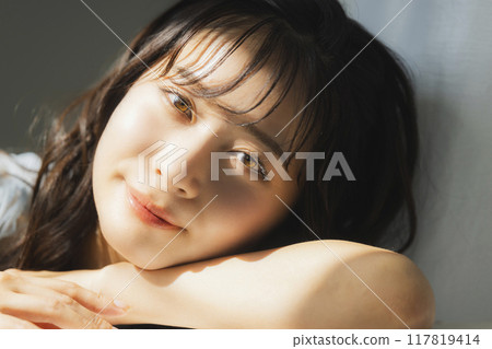 Woman by the window in the setting sun 117819414