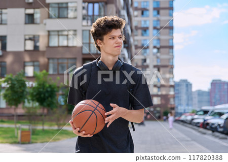 Young male with backpack basketball ball walking outdoors, modern city 117820388