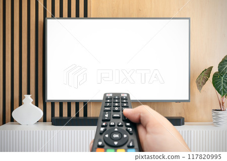 Man watching TV with remote control in hand. 117820995