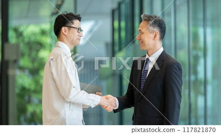 一名穿著工作服的男子和一名商人在大廳握手 117821870