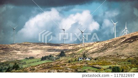 Few wind turbines stand tall on a hillside, capturing the wind's energy beneath a cloudy sky. Few wind turbines stand tall on a hillside, capturing the wind's energy beneath a cloudy sky. 117822697