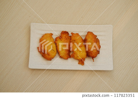 Corn croquettes on a white plate on a wooden table 117823351