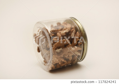 Walnuts in a plastic jar on a white background. 117824241