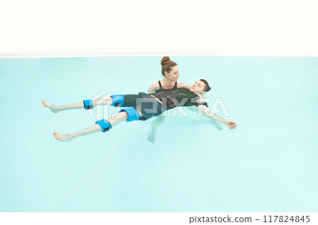 Two people in pool. Watsu man. Blue water rehabilitation massage. Aqua therapy Two people in pool. Watsu man. Blue water rehabilitation massage. Aqua therapy 117824845