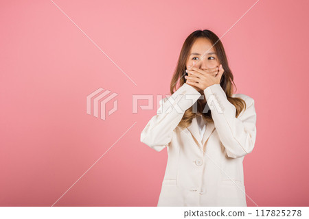 Asian happy portrait beautiful young woman standing smiling surprised excited her covering mouth with hands see only eyes and looking to camera on pink background with copy space for text 117825278
