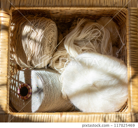 Sunrays filter through a basket with wool and natural yarns. Sunrays filter through a basket with wool and natural yarns. 117825469