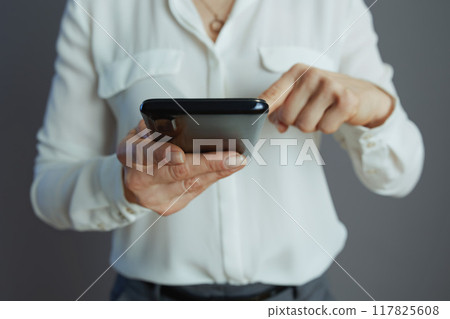 Stylish woman worker using smartphone isolated on grey Stylish woman worker using smartphone isolated on grey 117825608