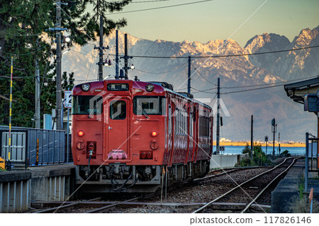 A red train parked at Amaharashi Station and a view of the snow-capped Tateyama mountain range A red train parked at Amaharashi Station and a view of the snow-capped Tateyama mountain range 117826146