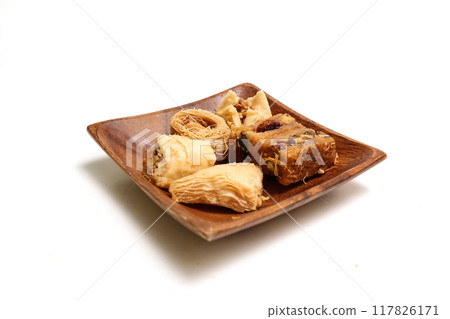Baklava in a wooden plate on a white background Baklava in a wooden plate on a white background 117826171