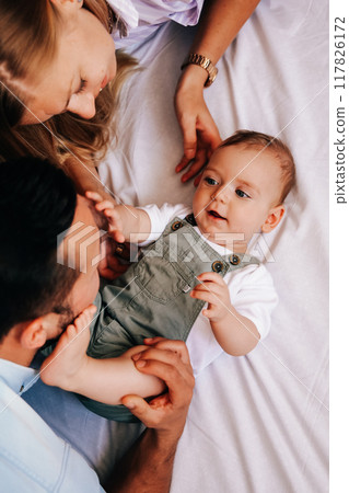 Young happy family. Careful young caucasian parents playing with their little cute baby boy.  117826172