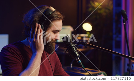 Sound producer recording backing vocals to add over tunes in home studio, using a mixing console to create a modern mix. Music producer mastering a new soundtrack with equalizer tool. Camera A. 117827110