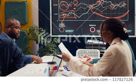 Team leader entering the meeting room and talking sense into his employees, trying to identify challenges or obstacles hindering progress. Supervisor and staff struggling with a project. Camera A. 117827126