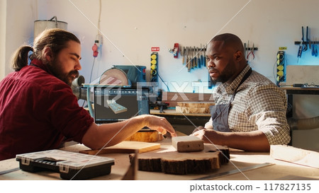 Happy BIPOC cabinetmaker and colleague comparing wood piece with schematic displayed on laptop. Cheerful carpenters in joinery crosschecking wooden object with notebook blueprint Happy BIPOC cabinetmaker and colleague comparing wood piece with schematic displayed on laptop. Cheerful carpenters in joinery crosschecking wooden object with notebook blueprint 117827135