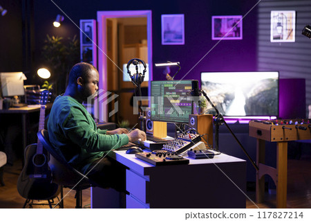 Audio composer playing piano electronic keyboard to create a new track, adjusting volume levels on old recordings. Music producer recording sounds, plays tunes on midi controller. Audio composer playing piano electronic keyboard to create a new track, adjusting volume levels on old recordings. Music producer recording sounds, plays tunes on midi controller. 117827214