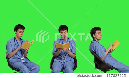 Health specialist is reading a literature book to acquire physician specialization and surgeon expertise, sitting in a chair. Nurse studying healthcare industry lecture against greenscreen. Camera B. Health specialist is reading a literature book to acquire physician specialization and surgeon expertise, sitting in a chair. Nurse studying healthcare industry lecture against greenscreen. Camera B. 117827225