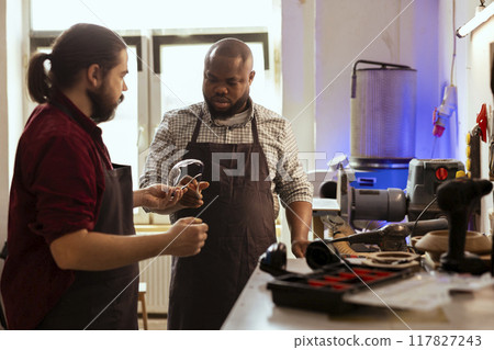 Master in woodworking shop giving BIPOC employee protection glasses before assembling furniture. Manufacturer preparing safety gear for african american apprentice before starting work 117827243