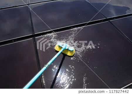 Cleaning dirty solar panels on flat roofs with a water-permeable deck brush 117827442