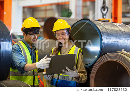 female and male wearing safety uniform worker use laptop checking quality product metal 117828280