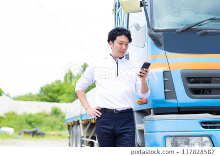Driver looking at smartphone in front of truck 117828587