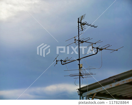 An old technology TV antenna in the evening sky on the roof. 117828864