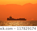 A boat sailing through the crimson sea in the evening 117829174