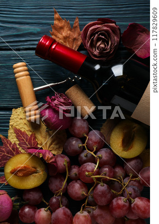 A bottle of wine on a dark background, with flowers and a snack. A bottle of wine on a dark background, with flowers and a snack. 117829609