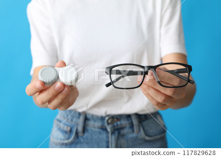 Glasses and a container for lenses in the hands of a woman 117829628