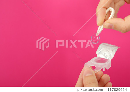 Plastic tweezers hold a clear eye lens close-up Plastic tweezers hold a clear eye lens close-up 117829634
