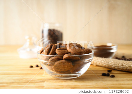 Cookies in the shape of coffee beans in transparent bowls Cookies in the shape of coffee beans in transparent bowls 117829692