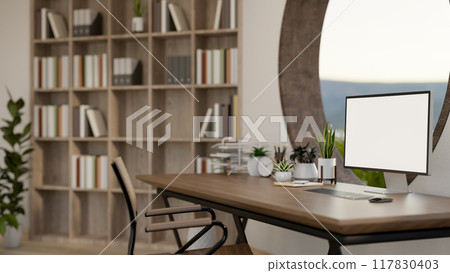 A computer mockup on a wooden desk against a round window in a contemporary room. 117830403