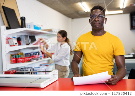 Employee of printing house checks the quality of printing in computer room 117830412