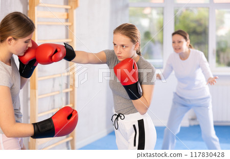 Women in boxing gloves punch deliver blow each other during training sparring session. Women in boxing gloves punch deliver blow each other during training sparring session. 117830428