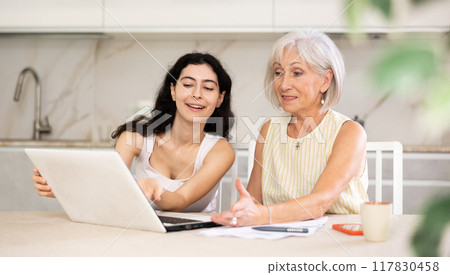 Elderly woman discussing deal with saleswoman in kitchen 117830458