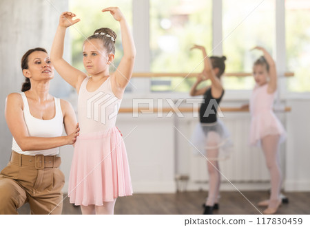 Woman teacher corrects movement of girl dancer Woman teacher corrects movement of girl dancer 117830459