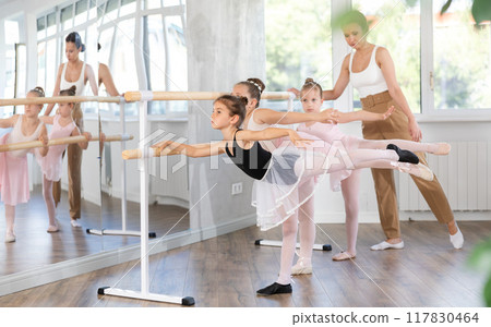 Woman teacher corrects girls in arabesque movement Woman teacher corrects girls in arabesque movement 117830464