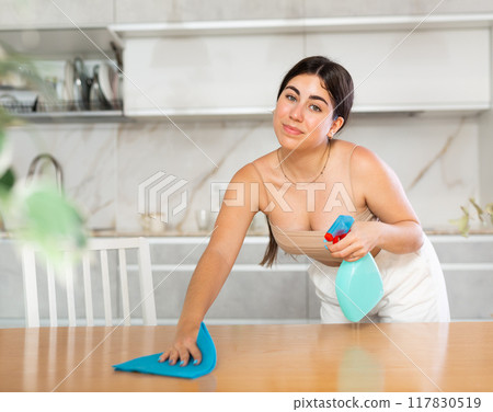 Young woman cleaning table in kitchen at home 117830519