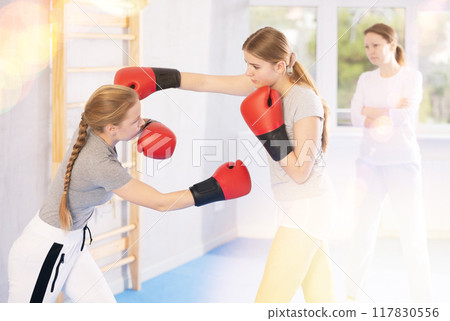 Women in boxing gloves punch deliver blow each other during training sparring session. Women in boxing gloves punch deliver blow each other during training sparring session. 117830556