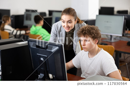 Teacher helping boy to solve computer problem 117830564