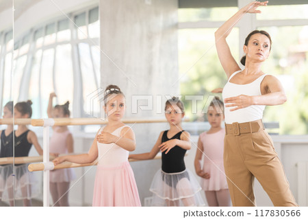Girl students of choreographic school look at woman teacher and repeat movements after her Girl students of choreographic school look at woman teacher and repeat movements after her 117830566